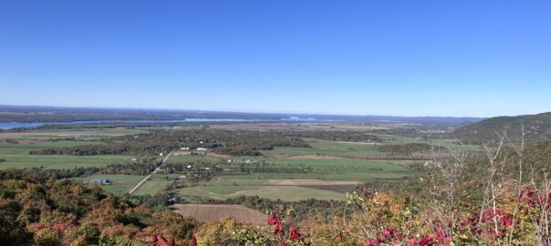 View from Champlain lookout over the eardley escarpment on a clear blue sky morning, with green fields, trees, highway and ottawa river in view. Fall colours just beginning to show.